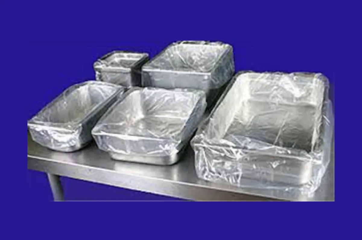 A table with several different sized pans wrapped in plastic.