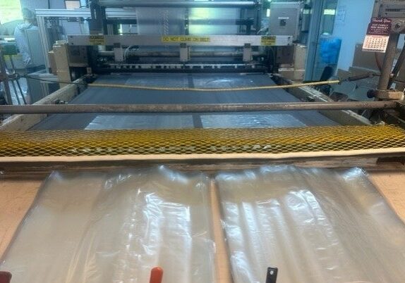 A machine is cutting plastic sheets for packaging.